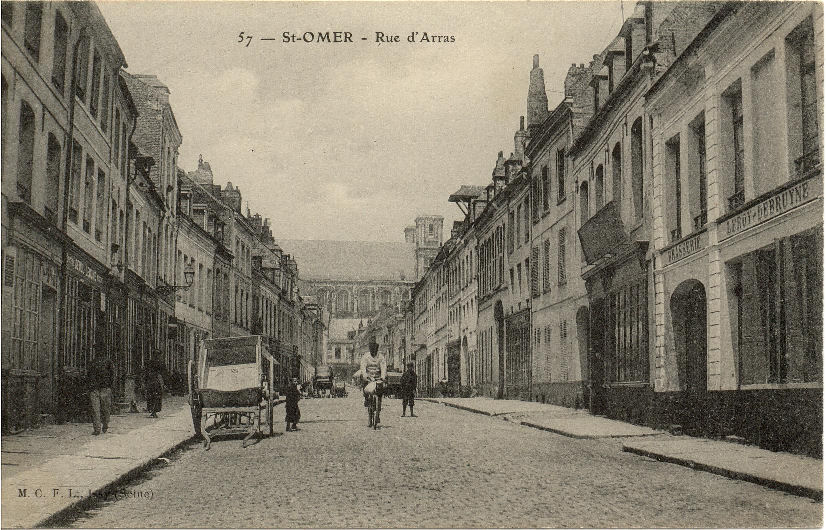 Sur la vue on peut voir une charrette à bras qui servait aux transport des marchandises.Avant 1894 se trouvait au bout de la rue la porte d'Arras que l'on empruntait pour rejoindre la route d'Arques.